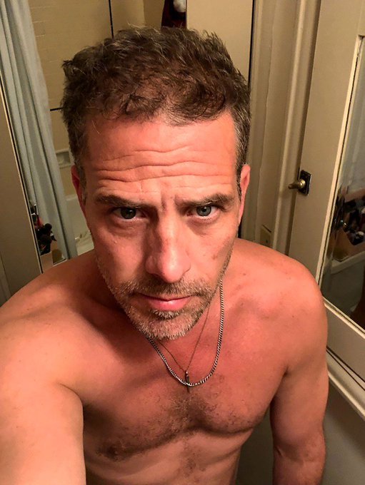 A shirtless man with short brown hair and a salt-and-pepper beard takes a mirror selfie in a bathroom, wearing two silver chain necklaces. The accompanying post about him logging off likely references the chaotic timing of the Hunter Biden memecoin launch, Kirk's assassination anniversary, and 9/11 falling in consecutive days.