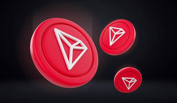 Three red circular coins featuring the TRON (TRX) logo float against a dark background, symbolizing the cryptocurrency's role in the accompanying post about Keeper wallet's "battery feature," which eliminates the need for users to hold TRX in advance to pay gas fees for USDT transfers on the TRON network.