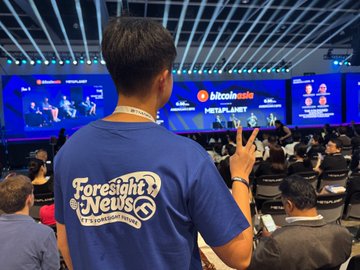 A person wearing a blue 'Foresight News' t-shirt stands in a conference hall, making a peace sign toward a Bitcoin Asia stage.