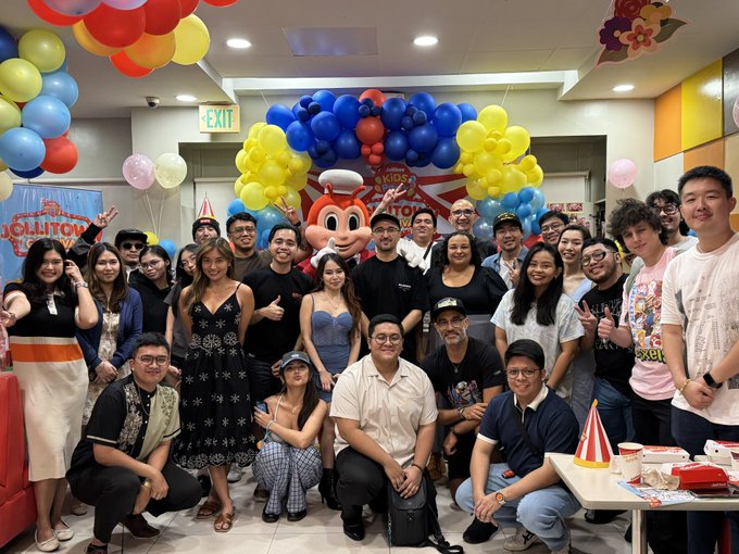A large group of smiling people pose together at what appears to be a BAYC (Bored Ape Yacht Club)-themed gathering, with a person wearing an ape mascot costume standing at the center amid colorful balloon decorations and a "JOLLITOWN" sign visible in the background. The celebratory scene captures the strong community bond described in the post, visually reinforcing the message that BAYC's true value lies in the meaningful connections and family-like relationships built through these monthly meetups rather than the JPEGs themselves.