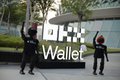 A group of people stand on a sidewalk next to a large white sign reading 'BAPE Wallet' with a graphic of a person.