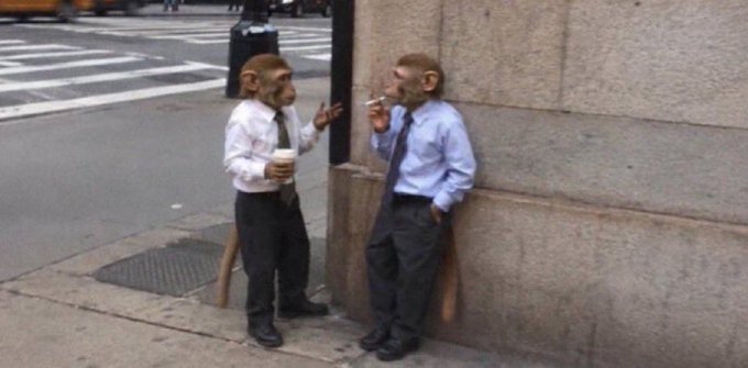 A humorous meme image showing two people with monkey heads wearing business attire having a smoke break on a city sidewalk.