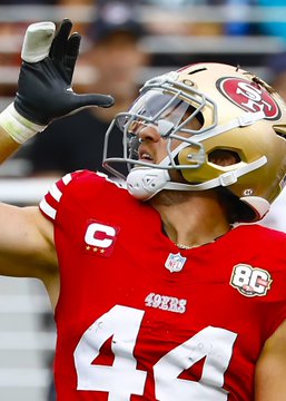 A player in a red jersey with the number 44 and a "C" captain's patch, wearing a San Francisco 49ers helmet, throws his hand up in a celebratory gesture. The image relates to the NFL's decision to rescind a fine against 49ers fullback Kyle Juszczyk for his "drinking" celebration, which the league clarified was meant to simulate drinking from a juice box.