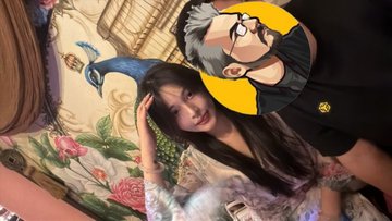 The image features a man wearing glasses, sitting next to a woman who has long hair. They are both posing for a picture together. The background of the photo includes a colorful painting or mural that adds an artistic touch to the scene. The caption at the bottom of the image reads "重生之我在越南地推币安 地推了一个小姐姐注册币安 @binance @binancezh @BinanceDesi".