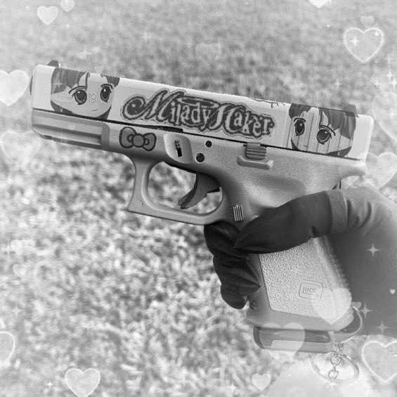 A black and white image of a hand holding a handgun decorated with anime art and the text 'Maid to Maker', with heart filter overlays.