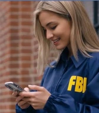 A smiling blonde woman wearing a blue jacket with "FBI" printed in yellow on it is looking down at her phone. The image humorously pairs with the caption suggesting she's an FBI agent monitoring or responding to someone's suspicious message about evading taxes using crypto mixers like Tornado Cash or Houdini Swap.