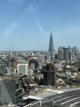 An aerial view of London's skyline featuring The Shard amid a dense cityscape, paired with a caption about enjoying a carefree trip with family in London while briefly noticing stock tickers like $IREN and $APLD on social media.