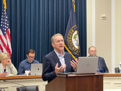 Ava Labs representative speaks at a podium during GBBC's #TechDemoDay congressional event, with an American flag and official seal displayed behind him as he addresses attendees including seated staff members.