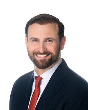 A professional headshot of a smiling bearded man in a dark suit and red tie, posed against a white background. The image appears to be a generic stock-style portrait with no visible text, names, or identifying information, making the connection to the White House Bitcoin reserve news unclear—it likely serves as a placeholder or stock photo in this context.