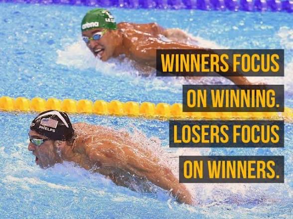 A motivational meme features swimmers Michael Phelps and Chad le Clos, with text reading 'WINNERS FOCUS ON WINNING. LOSERS FOCUS ON WINNERS.'
