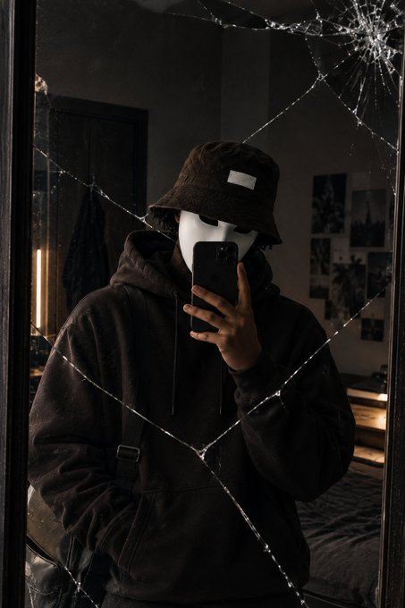 A mirror selfie of a person wearing a brown corduroy bucket hat and dark hoodie, with the mirror dramatically cracked and reflecting the phone camera.