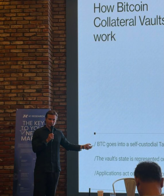 A presenter standing in front of a large screen during a K1 Research presentation titled 'How Bitcoin Collateral Vaults work,' with bullet points about BTC in self-custody and applications.