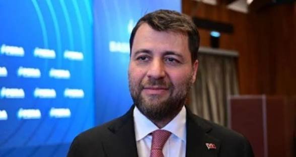 A man in a dark suit with a Turkish flag pin and pink tie smiles in front of a blue backdrop with repeating logos, suggesting a formal or political event. The post appears to speculate on potential financial consolidation involving BIST (Borsa Istanbul), possibly referencing this figure's connection to Turkish economic policies and the cryptocurrency $TERA.

Note: The image appears to show Berat Albayrak, former Turkish Treasury and Finance Minister, though no name is visible in the image itself.