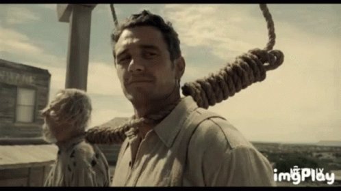 The image features a man wearing a brown shirt, standing against a backdrop of a building with a window. He has his neck tied up with a rope that is attached to a large hook or crane. The caption for this image reads "$LUNC holders to $BTC holders." This phrase suggests that the man's necktie is being used as a makeshift crane to lift something valuable, possibly money or an object of importance.