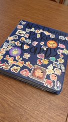 A Pokémon-themed zippered binder or pouch rests on a wooden surface, decorated with various character patches and stickers arranged around its border. The post suggests the collector recently used up their free Collectr credits without finding any rare or valuable Pokémon cards inside.