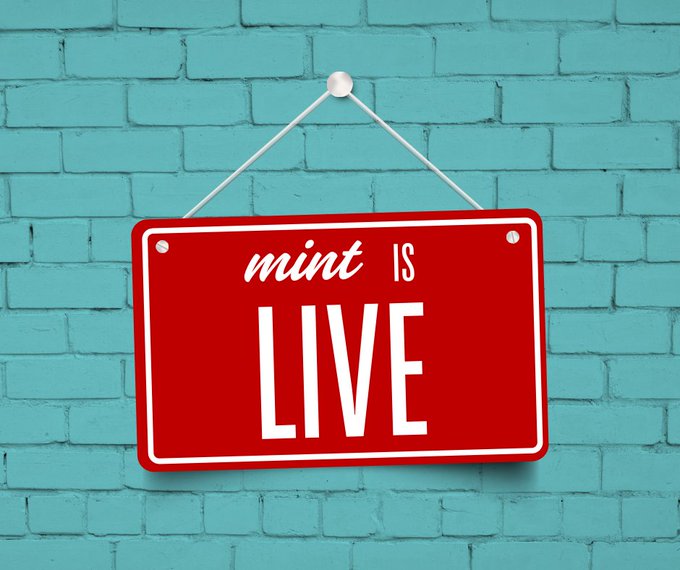 A red sign with white text reading "mint IS LIVE" hangs from a pin against a turquoise brick wall, announcing the launch of a mint event for a collection on OpenSea. The bold, eye-catching design emphasizes the live availability of the mint, directly matching the post's announcement for the cat collection on OpenSea.