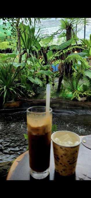 The image shows a glass of coffee sitting next to another cup, both placed on a table. The background features a view of water flowing down a river or stream, creating an interesting contrast between the calmness of the water and the hustle and bustle of everyday life captured in the scene. The post appears to be about coffee time, with the two cups symbolizing a moment shared over a warm beverage during what seems to be a weekend.

The caption "GM Một tách cà phê Một tâm trí bình yên Một các xa hơn" suggests that the coffee is served in a Vietnamese café, and it's likely to be a popular spot for people looking to enjoy their weekend.