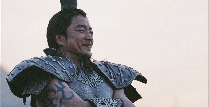 The image shows a smiling warrior in ornate armor with tribal tattoos, likely a scene from an Asian historical drama, which appears unrelated to the cryptocurrency exchange guide mentioned in the post.
