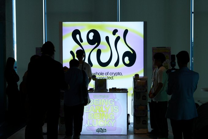 Silhouettes of people gathered in front of an illuminated booth displaying the 'gigio' logo with the tagline 'whole of crypto, connected,' and a podium reading 'BEING EARLY IS BEING LUCKY'.