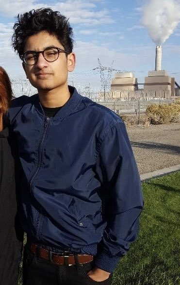 A young man with dark curly hair and round glasses, wearing a navy blue jacket, stands outdoors with a large industrial cooling tower emitting steam in the background, visually reinforcing the post's message about the memecoin market "cooling off" following FrankDeGods' exit, which triggered a $6.6B (16.7%) drop in total market cap within 24 hours.