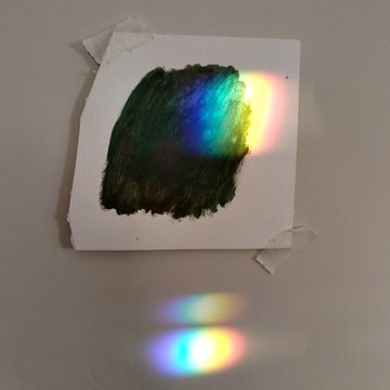 The image features a white paper with a green paint splatter, which appears to be a painting or drawing. The paper has been taped to a wall, possibly for display purposes. Below the paper, there's a post that reads "#TeiaWeave". This post seems to be related to the artwork on the paper, as it mentions "TeiaWeave" in its description.