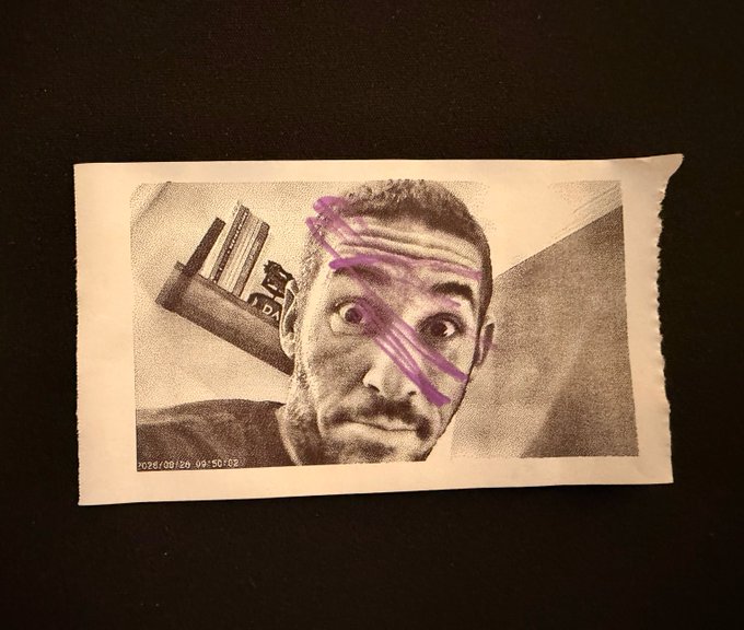 A torn black-and-white printed photo of a man with wide eyes and a surprised expression, with a purple 'X' drawn across his forehead, timestamped '2020/09/26 09:50:09'.
