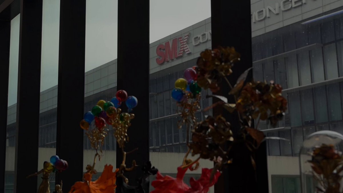 The image shows a large building with a sign that reads "SM" on top of it, possibly an office or warehouse for a company. The building has many windows, indicating its size and prominence within the cityscape. In front of the building, there are several colorful balloons tied to the structure, adding a festive touch to the scene. A potted plant is also visible in the foreground, further enhancing the visual appeal of the image. The post features an announcement about a special event happening only 3 days left and encourages people to join us at #PhilippineBlockchainWeek for more information on this exciting opportunity.