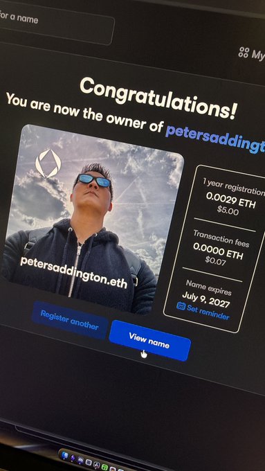 A computer screen showing a 'Congratulations!' message for registering the domain 'petersaddington.eth', displaying a profile photo of a man with sunglasses and registration details including 0.0029 ETH and expiration date July 9, 2027.