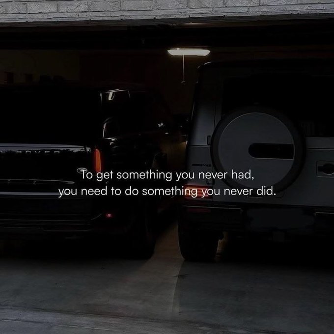A dimly lit garage shows two parked SUVs (one appearing to be a Land Rover) with overlaid inspirational text reading, 'To get something you never had, you need to do something you never did.'