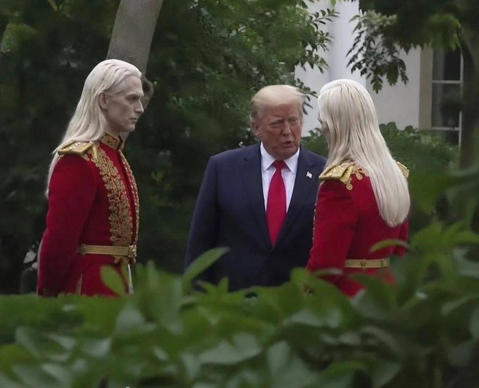 The image features a man wearing a suit, standing next to two white statues of men dressed in red suits with gold accents. The man in the center has blonde hair and is wearing a tie. One of the statues appears to be a person, while the other resembles an elf or a dragon figure. The statues are positioned close together, creating an interesting visual effect.

The image also contains text that reads "Rumors circulating that Trump and these Elves were discussing the Strategic Bitcoin Reserve". This suggests that there might have been some speculation or discussion about the Strategic Bitcoin Reserve between the man in the suit and the two white figures with gold accents.