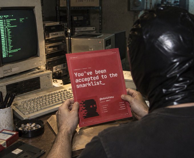 A person in a black hood holds a red paper that reads "You've been accepted to the snarklist_" with the handle "@ablablablaaw" in front of an old computer setup.