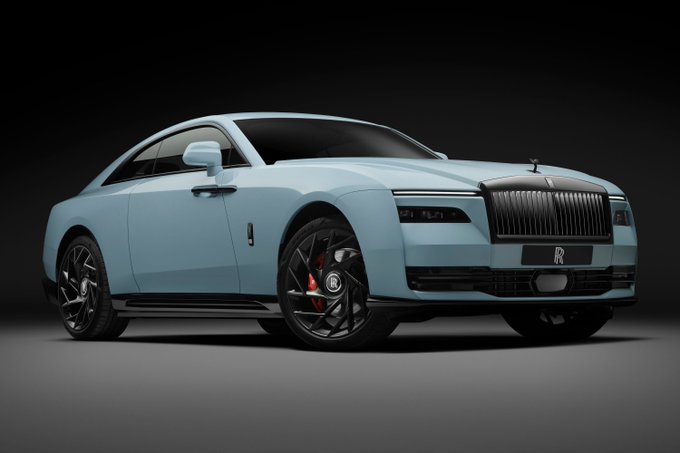 A light blue Rolls-Royce Spectre coupe is shown in a studio shot against a dark background, featuring the iconic Spirit of Ecstasy hood ornament and the 'RR' license plate.