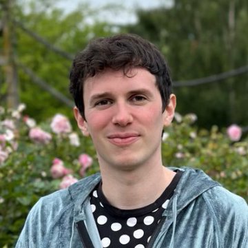 A man with short dark hair, wearing a gray hoodie over a black and white polka dot shirt, stands outdoors in front of pink roses and green foliage. The image appears to be a portrait associated with James Fickel, the trader mentioned in the post who transferred 20,000 ETH ($36.19M) to a new wallet after previously losing a significant sum on a long ETH/BTC position.