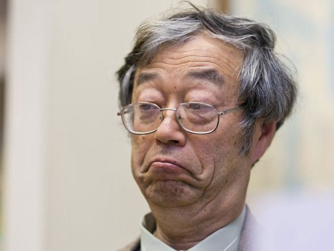 A close-up portrait of an older East Asian man with gray hair and rectangular glasses, wearing a light-colored shirt, with a thoughtful or slightly somber expression.
