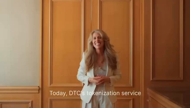 A woman wearing a white blazer stands in front of an orange wall with text that reads "Today, DTCC tokenization service" and "DTCC tokenized assets will be available on Stellar".