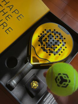A yellow and black ping pong paddle set, including a paddle, ball, and wristband, is shown in its packaging with the text "SHAPE HERE HERE" visible, presented as a BNB Chain 6th anniversary gift box from @BNBCHAINZH and @0xsandy1913 to celebrate the Mid-Autumn Festival and promote exercise among builders.