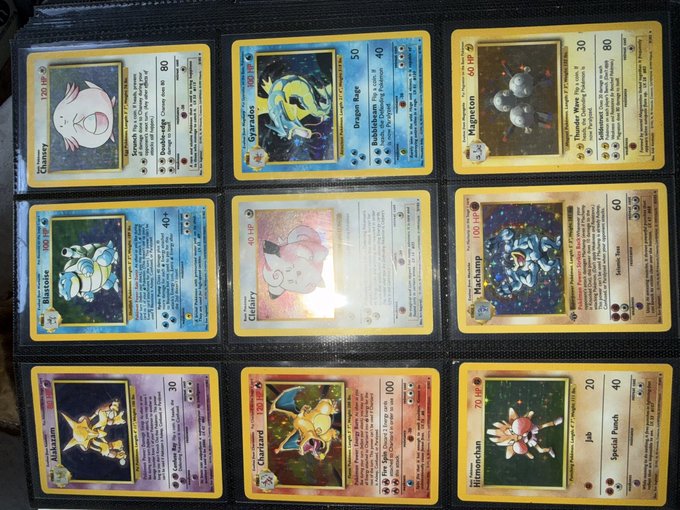 A vintage Pokémon card binder is opened to display nine holographic cards including Chansey, Gyarados, Magneton, Blastoise, Clefairy, Poliwrath, Kadabra, Charizard, and Hitmonchan, with attack damage numbers like 80, 50, and 100 visible. The collection appears to feature classic first-generation holographic cards, likely being shown off to gauge their collector's market value in the context of cryptocurrency trading.