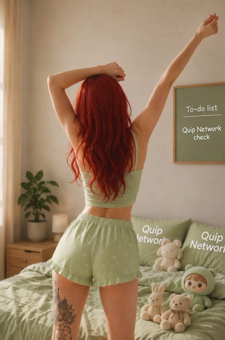 The image features a woman with red hair wearing green pajamas standing in front of a bed. She has her arms raised up in the air, as if she's greeting someone or celebrating something. The room also contains several stuffed animals on the bed, including two teddy bears and a bunny. There is a poster hanging on the wall that says "To Do List".