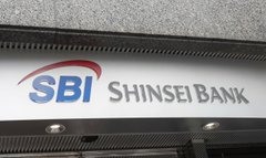 The image features a building with a sign that reads "SBI Shinsei Bank". Below this, there's an announcement about a new currency called the yen stablecoin. The yen stablecoin can be used for large-value settlements without Japan's ¥1 million transfer cap and is backed by SBI Shinsei Bank.