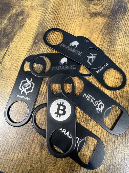 A collection of black metal bottle openers engraved with various cryptocurrency and technology logos, including Bitcoin, Parasite, and NerdQ, along with the text "lxtech.xyz".