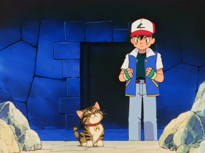 An anime-style illustration of Ash Ketchum standing next to a smiling tabby kitten wearing a red collar with a bell, set against a blue stone wall.