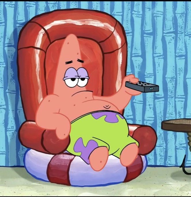 Patrick Star from SpongeBob SquarePants lounging lazily in a red armchair, wearing a green blanket with purple spots, holding a TV remote with a bored expression.