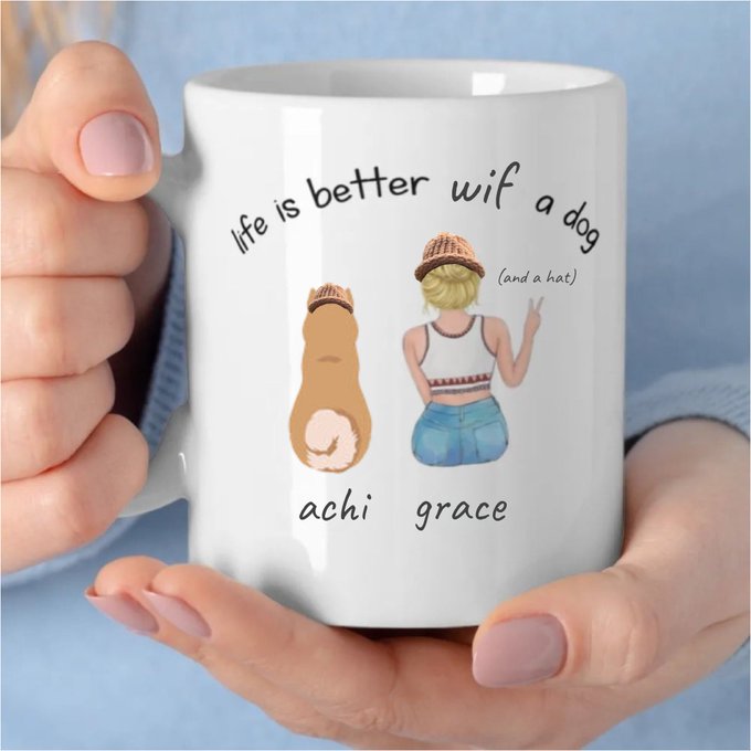 A pair of hands holds a white ceramic mug featuring an illustration of a girl and her dog both wearing matching hats, with the text "life is better wif a dog (and a hat)" and the names "achi" and "grace" printed below the figures.
