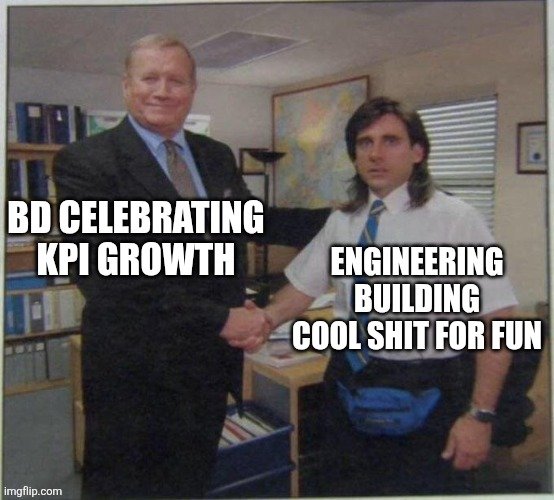 A meme based on a photo from The Office, showing two men shaking hands with overlaid text: 'BD CELEBRATING KPI GROWTH' on the left and 'ENGINEERING BUILDING COOL SHIT FOR FUN' on the right.