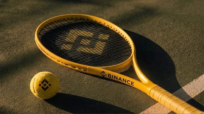 A yellow tennis racket branded with "BINANCE" and a matching tennis ball sit on a court, visually tying the "GM" (Good Morning) post to a sport-themed reference, likely celebrating Binance's involvement in or sponsorship of tennis.