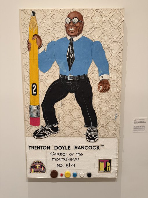An artwork by Trenton Doyle Hancock titled 'Creator of the moundiverse No. 5174', depicting a smiling character holding an oversized yellow pencil.