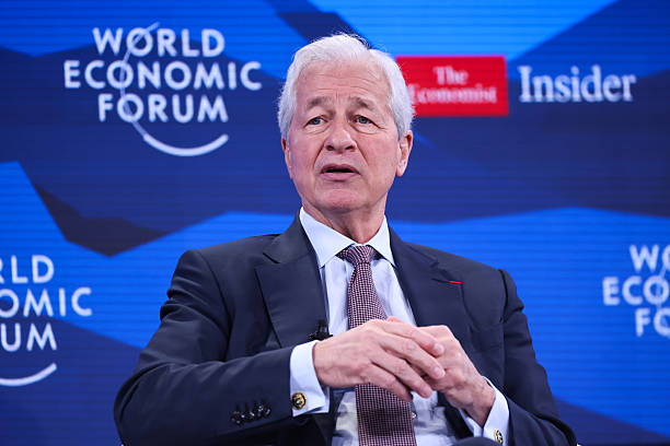 A man in a suit speaks at the World Economic Forum, with logos for "World Economic Forum," "The Economist," and "Insider" visible behind him. The image relates to the post by being a likely photo of JPMorgan CEO Jamie Dimon, who famously called Bitcoin a fraud in 2017.