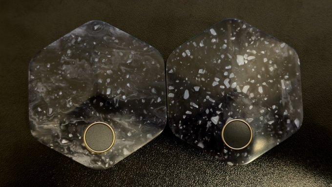 Two hexagonal, speckled metal backplates of Bitkey hardware wallets are shown side by side, each featuring a small circular element near the bottom. The unique, irregular pattern on each plate visually supports the caption's claim that each Bitkey is distinct, making it difficult for an attacker to swap or replace the hardware unnoticed.