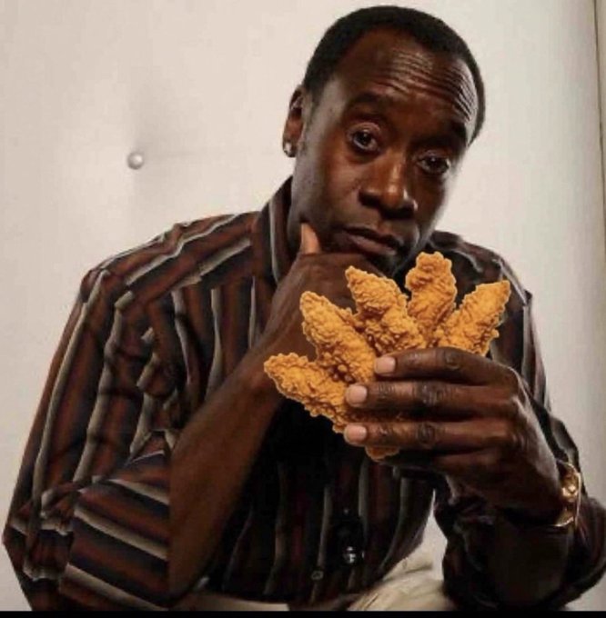 A man wearing a striped shirt holds several pieces of fried chicken near his face, resting his chin thoughtfully on his hand.
