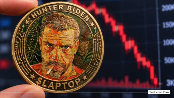 A hand holding a novelty "HUNTER BIDEN $LAPTOP" crypto coin in front of a red downward-trending stock market chart, with "The Crypto Times" watermark visible.